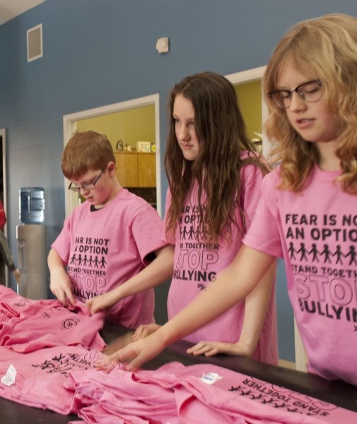 (From left) Blake Lamoureux, Holly Rowe and Grace Kloster sort through the piles of pink shirts at the Boys and Girls Club of Cochrane and Area on Feb. 21.
