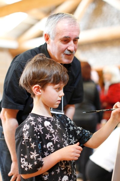 Landscape artist Andrew Kiss watches over Kai Goodlet as he tries his hand with a paint brush. Kiss will be one of the artists coming to the Cochrane RancheHouse for the