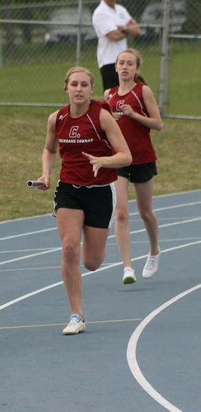 Cochrane High School Cobras track team members Shannon Denison (rear, just handed off baton) and Kayla Sage are two of 13 Cobra girls headed to the Nike Grand Prix