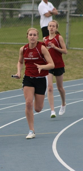 Cochrane High School Cobras track team members Shannon Denison (rear, just handed off baton) and Kayla Sage are two of 13 Cobra girls headed to the Nike Grand Prix