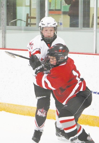Foothills forward Justin Turko (front) takes a body-check from Calgary Rage forward Wilson Steele in Foothills Elite Peewee AAA Spring Ice Breaker hockey tournament play