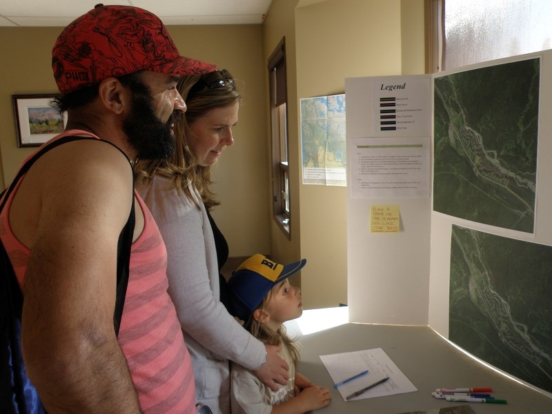 The Milnes family looks at a display detailing different proposed trail options connecting Redwood Meadows to Bragg Creek, at the Sustainable Redwood Open house held at