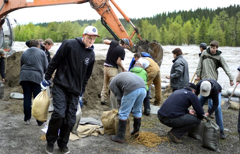 Redwood Meadows residents frantically sandbag at a portion of the berm threatened by the Elbow River on June 20.