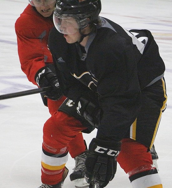 Cochrane&#8217;s Coda Gordon fights off a check during a Calgary Flames prospects camp scrimmage July 15 at WinSport&#8217;s Markin MacPhail Centre in Calgary.