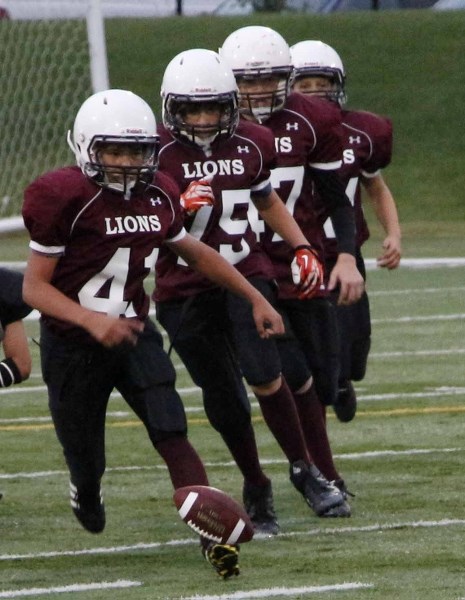 There&#8217;s only one ball to go around for the Cochrane Lions, led by Jack McNair, during Calgary Peewee Football Association play against Airdrie Storm Aug. 29 at