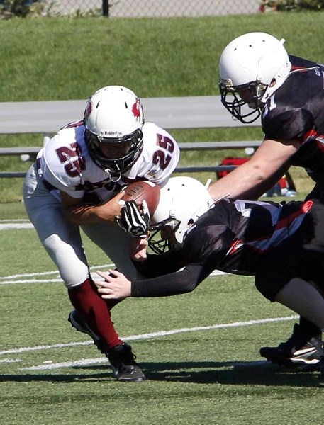 Cochrane Lions ball-carrier Jackson McLean runs into Airdrie Raiders defenders during Calgary Bantam Football Association play Aug. 31 at Calgary&#8217;s Shouldice Park. The