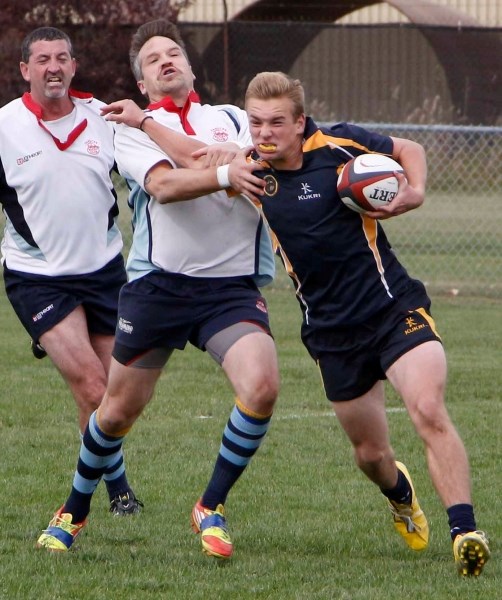 Bow Valley Grizzlies ball-carrier James Patterson works over Calgary Canucks tacklers while sprinting for daylight in Calgary Rugby Union Division 3 men&#8217;s city final