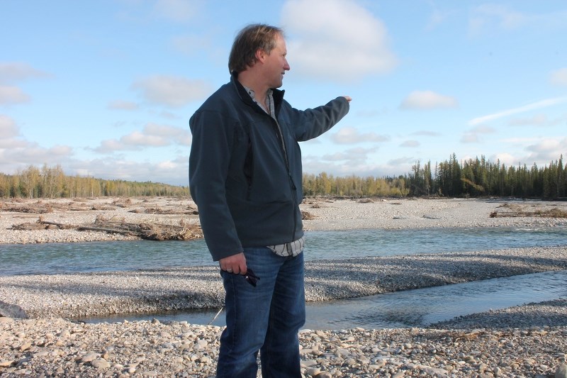 Redwood Meadows mayor John Welsh stands on his community&#8217;s berm to survey the new path of the Elbow River. The berm prevented the townsite from flooding in June, but