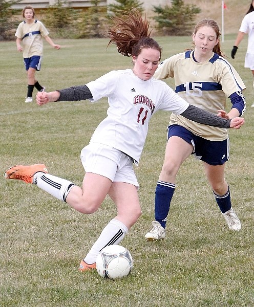Cochrane High School Cobras Anna Kennedy boots the ball as Bow Valley High School Bobcats&#8217; Jessica Youngblood moves in on the play during South Central Zone high school 