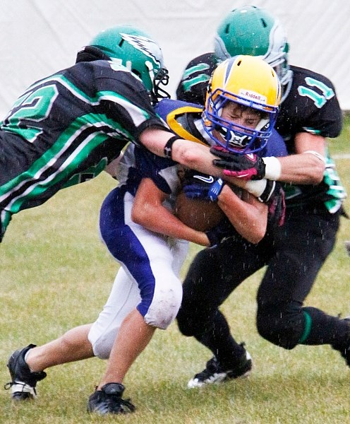 Springbank High School Phoenix tacklers Tristin Bobier (left) and Devin Smith grab Bert Church High School Chargers kick-returner James Spencer in Rocky View Sports