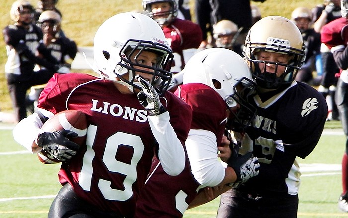 Cochrane Lions running back Dylan Neis takes off with the ball as teammate Isaiah Springer throws a block in Calgary Peewee Football Association season-ending play against