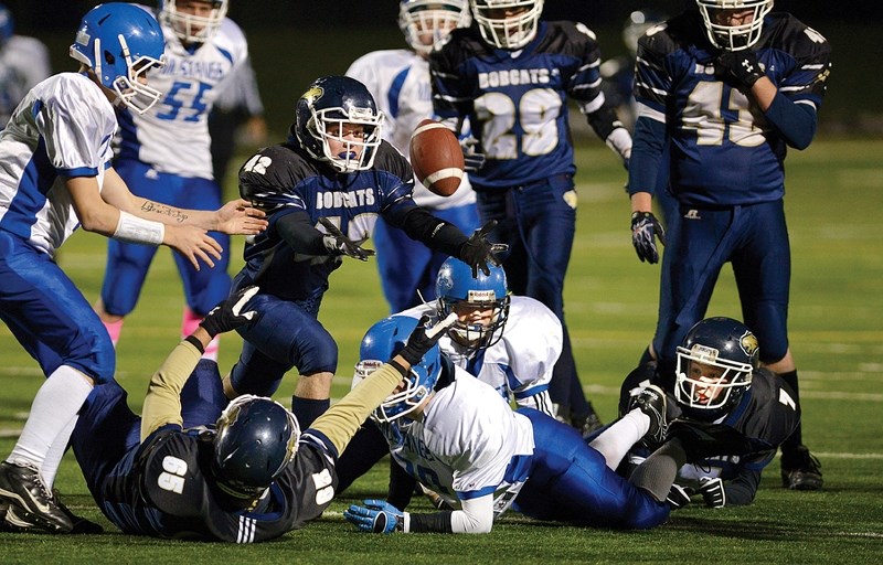 Bow Valley Bobcats defender Cole Perron (reaches for the ball in Alberta Schools&#8217; Athletic Association regional playoff football action against the Highwood Mustangs of 