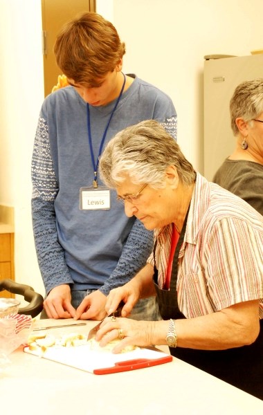 Lewis Talbot, a Grade 11 student at St. Timothy School, whips up Ukrainian meat pies under the watchful eye of Yvonne Veldhuis at Seniors on the Bow Dec. 12. The pair are two 