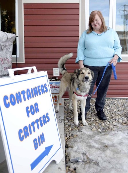 Nancy Butterfield and Watson, a one-year-old Cochrane and Area Humane Society pup, pose with the Containers for Critters bin Dec. 27. The bin is used as a bottle drive to