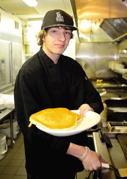 Kyle Faber, a line cook at Smitty&#8217;s, holds up a plate of pancakes March 11. Smitty&#8217;s will be hosting a pancake breakfast March 19 from 7 a.m. to 2 p.m. to benefit 
