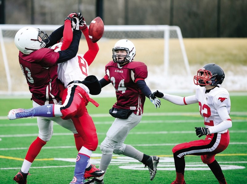 Cochrane Lions receiver Evan Perrault has a pass swatted away as teammate Scott Haigh (right) moves in on the play in Calgary Area Midget Football Association play April 12