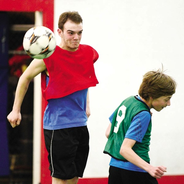 Cochrane High School&#8217;s Olivier Roy (left) heads the ball past Adam Ulisnyak in Cochrane High School Cobras boys soccer tryouts April 12 at Spray Lake Sawmills Family