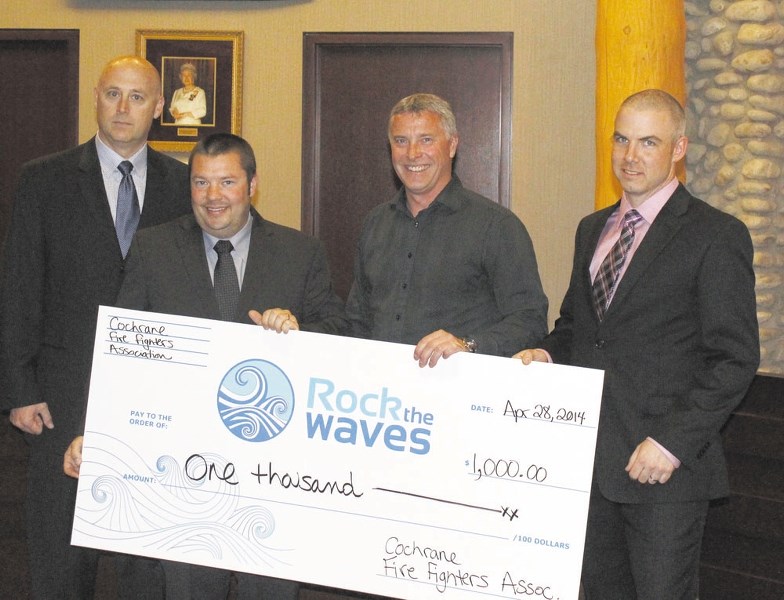 Cochrane firefighters Scott Pletsch, left, Rob Olenick and Russ Innes, far right, present a cheque for $1,000 to Mayor Ivan Brooker during the April 28 council meeting on