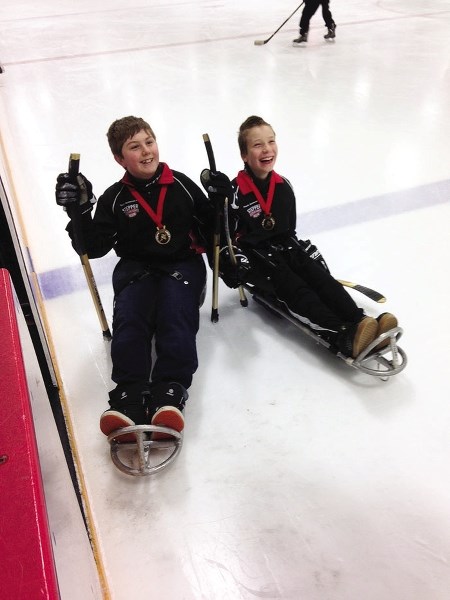 Eric Carvelli (from left) and Shane Mott display the gold medals they won at the regional sledge hockey tournament in Leduc earlier this month. Playing for Calgary Venom, the 