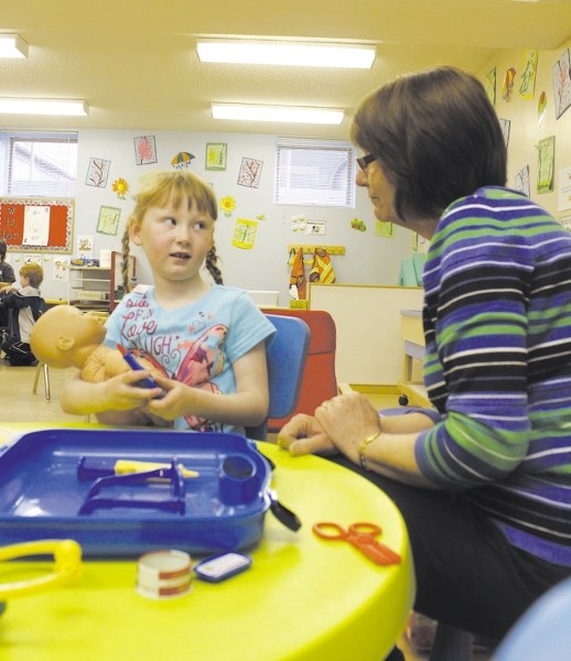 Sarah Blackett, a teacher at the Cochrane Creative Playschool Society, helps four-year-old Sophie Ashton doctor her baby doll during play time at the playschool April 30.