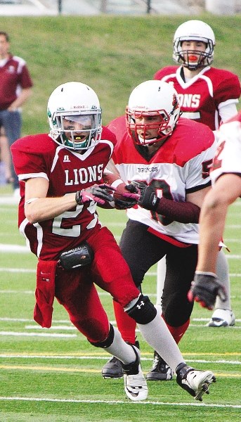 Cochrane Lions running back Devin Smith chews up yardage against Calgary Broncos in Calgary Area Midget Football Association play May 14. Smith had a TD in Lions&#8217; 38-21 