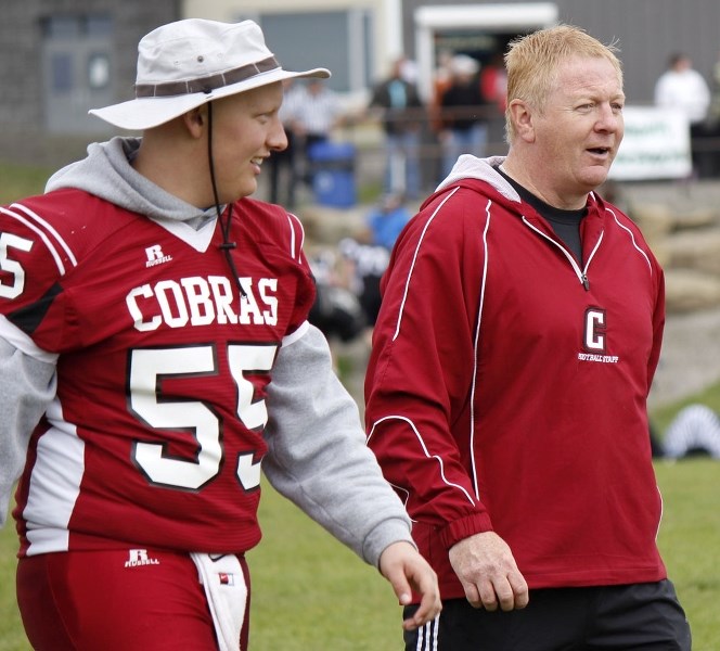 Cochrane Cobras centre Brock Wiebe and defensive-backs coach Jeff Avery hike across the field between scrimmages at the June 14 Holy Trinity Academy Knights football jamboree 