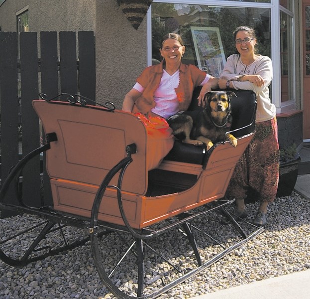 From left: Patricia Gustafson, dog Molli and Hannah White display the sleigh.
