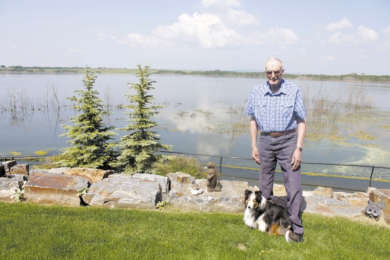 Monterra resident Alex Cummings, 86, stands in his backyard overlooking Cochrane Lake with his Sheltie, Kelsey. The unprecedented water levels have significantly impacted