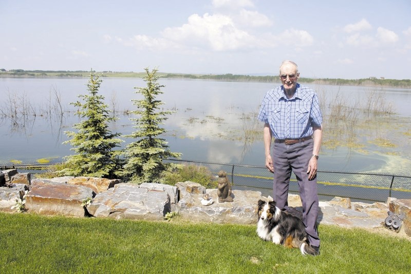 Monterra resident Alex Cummings, 86, stands in his backyard overlooking Cochrane Lake with his Sheltie, Kelsey. The unprecedented water levels have significantly impacted
