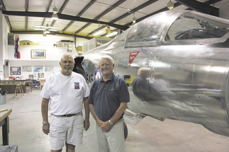 Cpl. Gary Watson (left) and Col. Gerry Morrison stand by the CF-104 Starfighter they are restoring at the Springbank Airport on July 20. The plane will be displayed at the