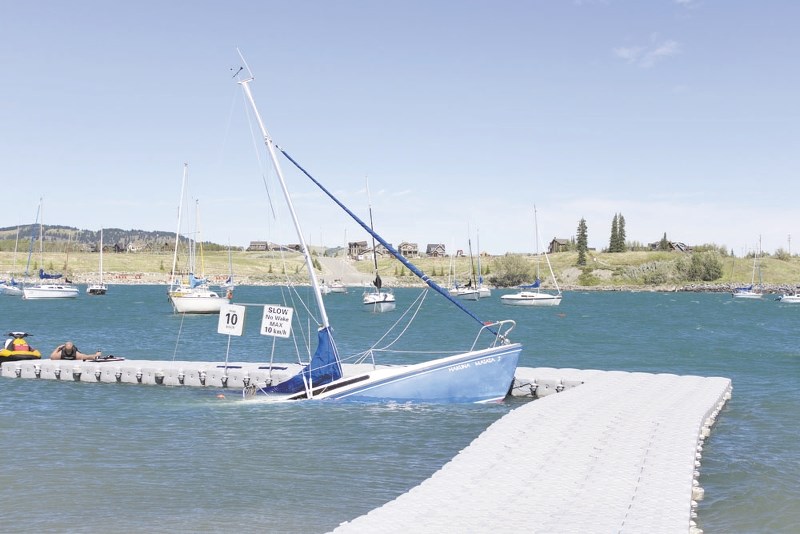 A boat slowly sinks into Ghost Lake July 24, as high winds and waves caused everything on the water to be tossed around.