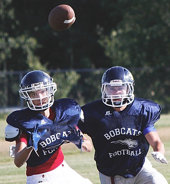 Bow Valley High School Bobcats (from left) Aaron Karaja and Scott Haigh spy the ball during passing drills at the school&#8217;s opening day of training camp Aug. 25.