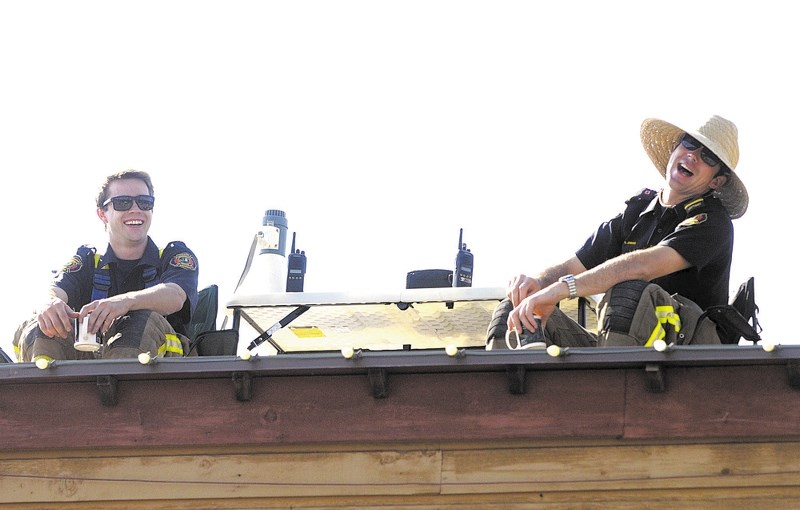 Firefighters Chad Gibson, left, and Russ Jenkins sit atop Bragg Creek Family Foods during the Heroes in the Sky event.