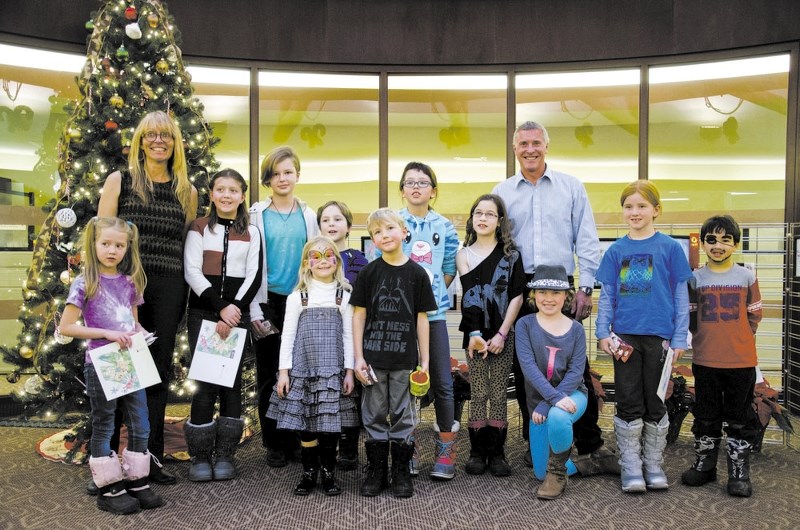 Art instructor Jola Muran and Mayor Ivan Brooker stand with art students from the town&#8217;s art development and art exploration classes Dec. 12. The students created