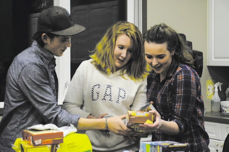 Bragg Creek Community Church youth group members Levi Harder, 16, and sisters Rachael, 16, and Cassidy McCardle, 18, help assemble food hampers Dec. 19.