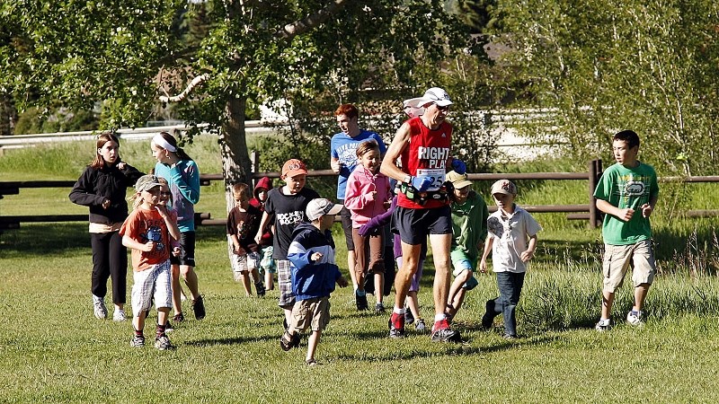 Martin Parnell running with a group of kids from Cochrane Day Camp on his 125th marathon at the Historic Cochrane Ranche site, the halfway mark of his quest to run 250