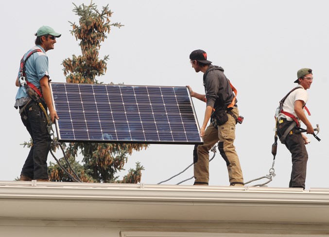 Employees install solar panels onto the Maloney&#8217;s roof on Aug. 23.