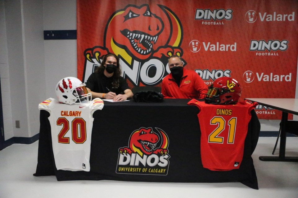 Jacob Mate signs his commitment letter alongside Dinos head coach Wayne Harris at the University of Calgary campus on Oct. 26. Photo submitted.