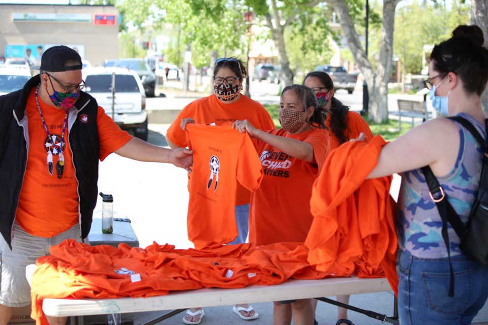 John Sedo, left, and Buffy Bearspaw hold up an orange shirt at the memorial site alongside fellow volunteers Laura Bearspaw and Lynn Bearspaw on Thursday (June 2). (Tyler Klinkhammer/The Cochrane Eagle)