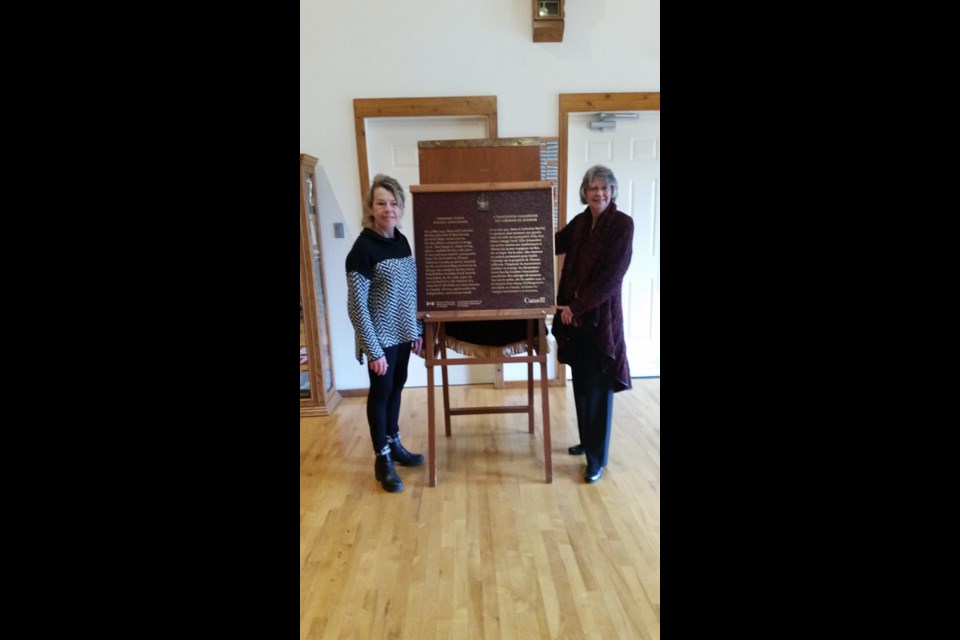 Bragg Creek Historical Society director Michele McDonald, left, and president Judy Norman unveil a plaque commemorating the Bragg Creek Youth Hostel. Submitted Photo