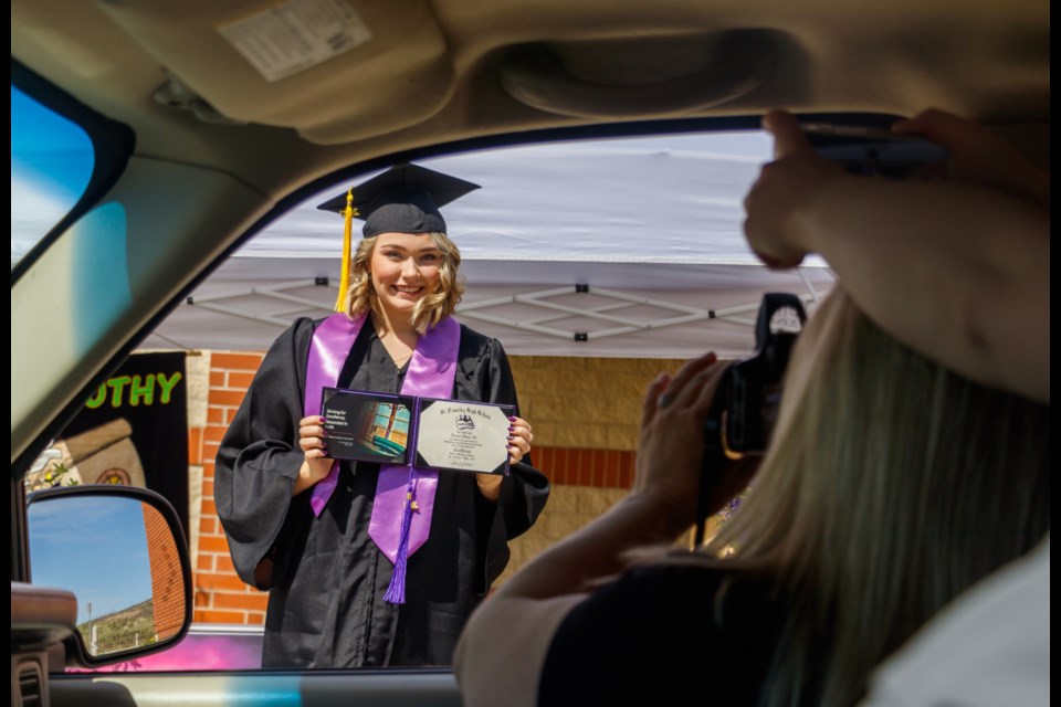 Jacelyn Ek, 18, poses for a photo with her diploma at St. Timothy’s Junior/ Senior High School drive by graduation ceremony on Friday (May 29). (Chelsea Kemp/The Cochrane Eagle)