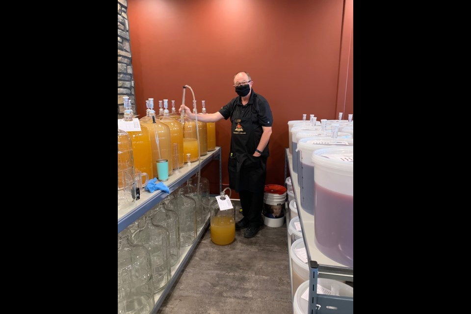 Co-owner of Vintner's Cellar, Stuart Ray, siphon's wine from one glass container to another. Photo submitted.