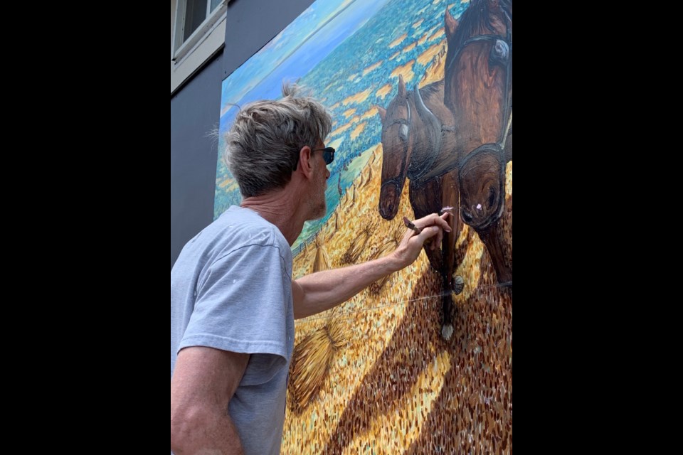 Allan Bender is shown working on the Our Community mural in Collingwood.