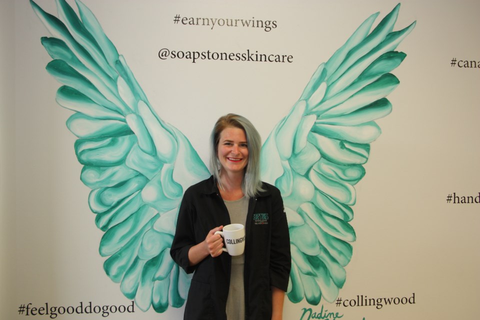 Andrea Crane is the manager at Collingwood Soapstones. She's posing in front of the store's set of wings, meant to help customers feel good about their purchases. Erika Engel/CollingwoodToday