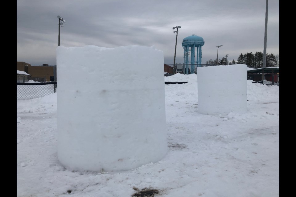 Six-foot cylinders of packed, man-made snow wait in the ball diamond at Central Park for tomorrow's amateur snow carving competition. Erika Engel/CollingwoodToday