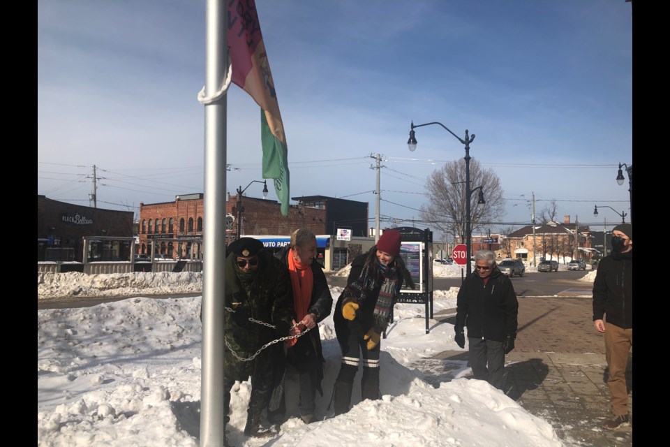 Bam528!, Marcia Alderson, and Jillian Morris raise the Black History Month flag at the town flag pole located at the Collingwood Public Library on Feb. 1, 2022. 