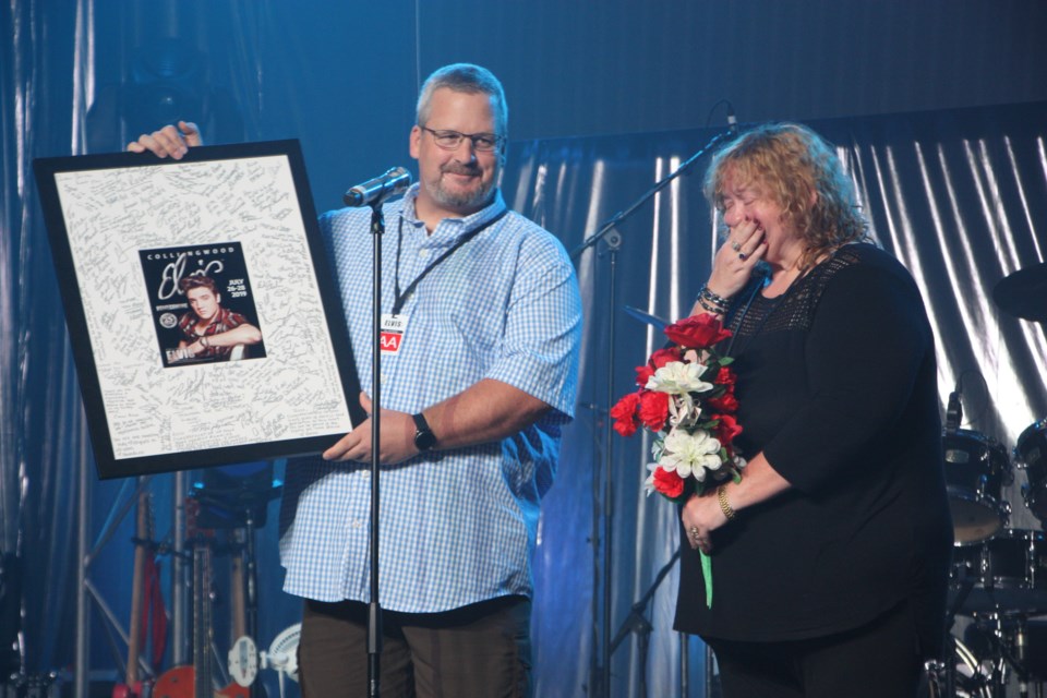 Dean Collver surprises Rosemarie O'Brien with a copy of the 25th anniversary Collingwood Elvis Festival souvenir program in a frame signed by every participating ETA and all the festival staff. The crowd rose to its feet to thank O'Brien for 23 years organizing and planning the festival. Erika Engel/CollingwoodToday