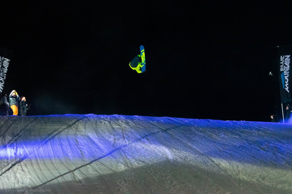 A snowboard athlete takes a turn on the 50-foot jump.