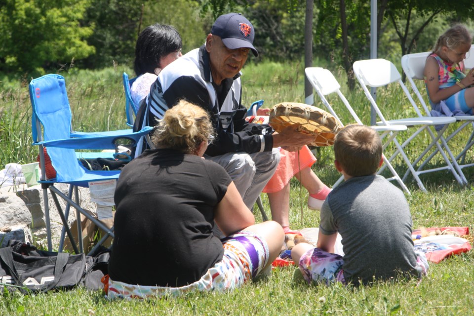 James Kwaquom teaches a child before speaking to the crowd at the change of seasons ceremony on June 18. 
