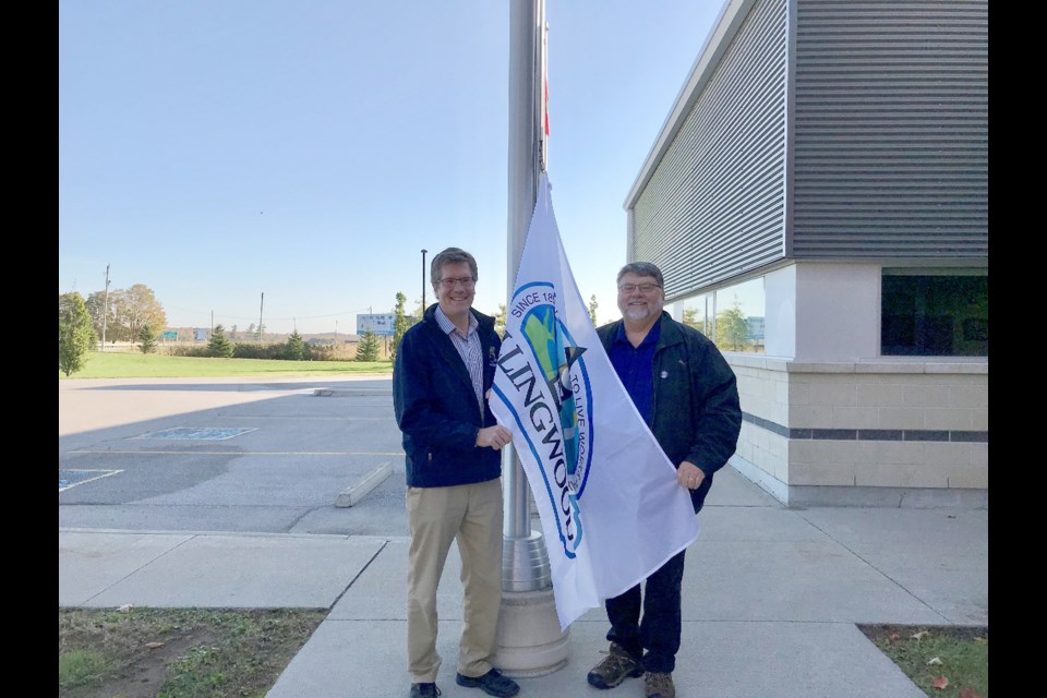 Mayor Brian Saunderson and Clearview Township mayor Doug Measures raise the Collingwood flag in Stayner. Contributed photo